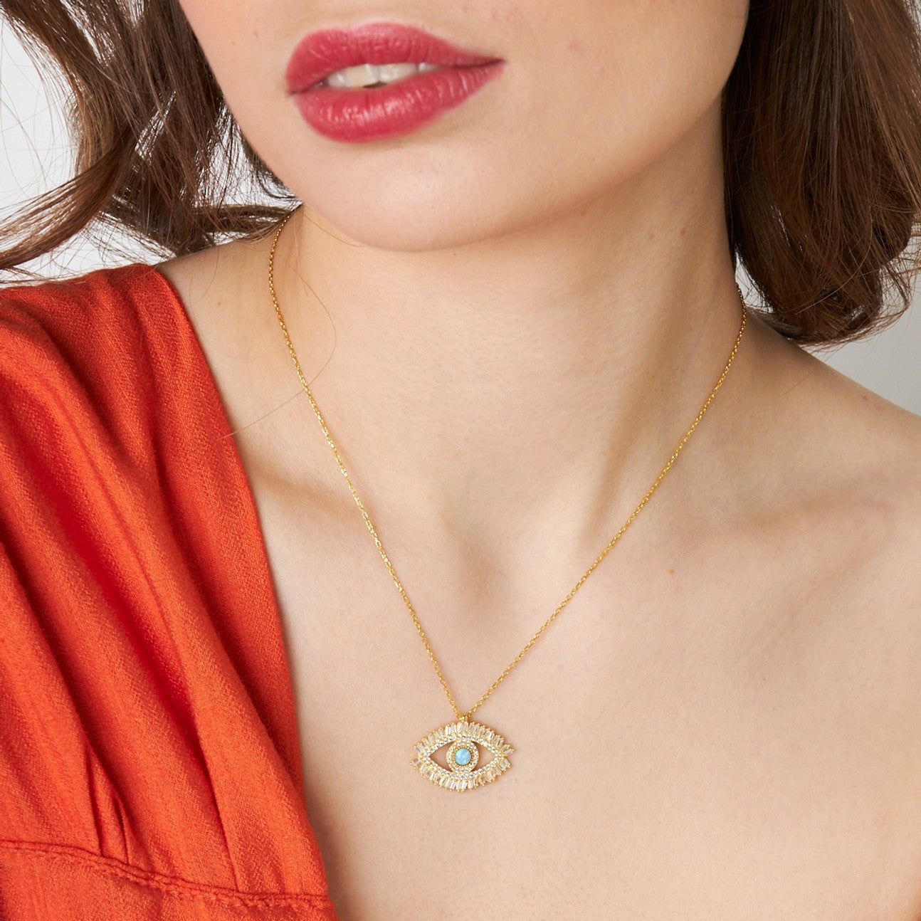 14K gold Augen Halskette mit Baguettesteinen, elegant getragen von einer Frau in einem roten Oberteil.